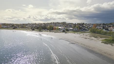 Aerial drone shot over Ringshaugstranda Beach near Tønsberg, Norway, with soft sunlight peeking through scattered clouds