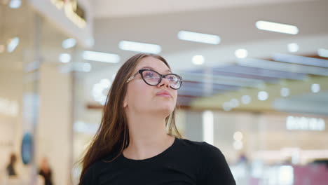 dama blanca con gafas con el cabello largo en cascada sobre su hombro, mirando a un lado y alardeando su cabello con luz brillante, en el entorno vibrante del centro comercial con fondo borroso