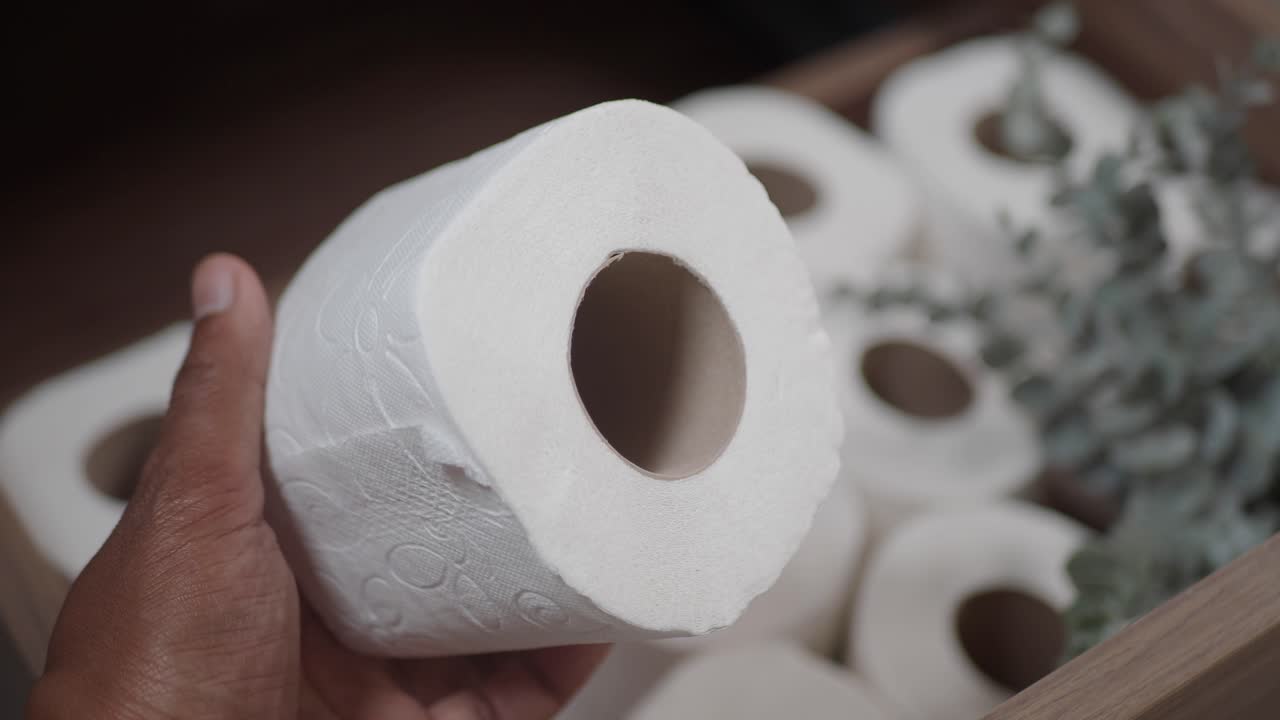 Hand holding a roll of toilet paper in a drawer