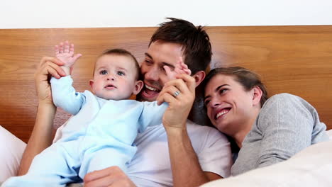 Happy-parents-lying-on-bed-with-baby-son