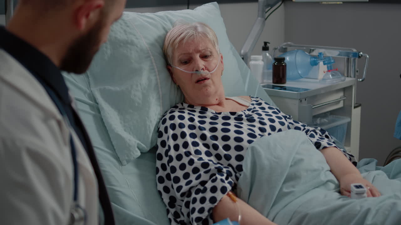 Close up of elder patient laying in bed and talking to medic