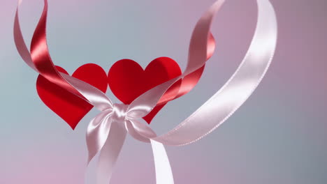 two red hearts with a white ribbon bow