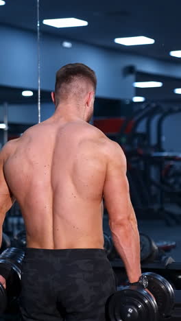 muscular man working out with dumbbells in gym