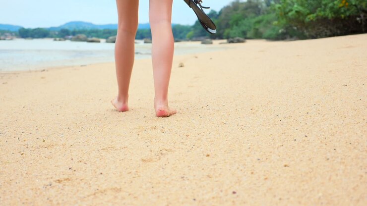 Una bella ragazza passeggia a piedi nudi su una spiaggia esotica e sabbiosa in Asia.