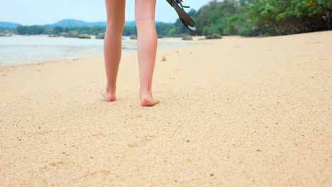 a beautiful girl is taking a walk barefoot on a sandy, exotic beach in asia