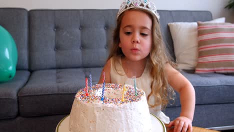 chica soplando velas en el pastel de cumpleaños