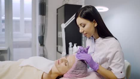 young beautiful dark-haired woman gets rejuvenating facial injections. work of the cosmetologist.