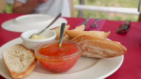 Pieces-of-bread-with-bowl-of-butter-and-tomatoes-typical-spanish-food-close-up