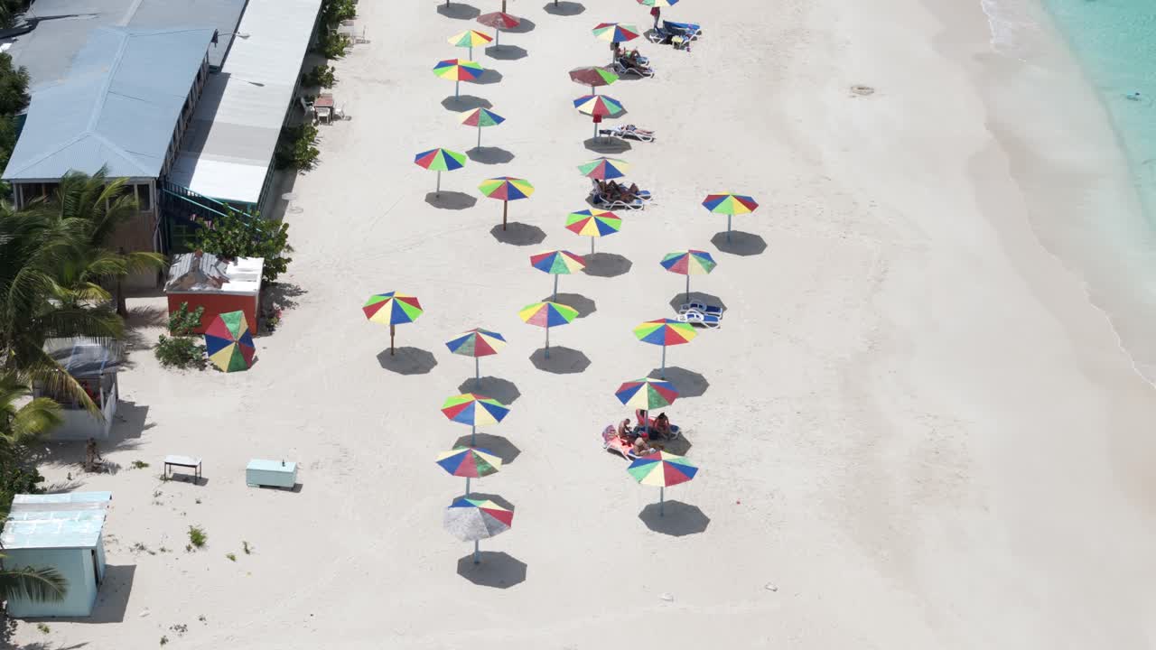 Colorful Parasols And Restaurants At Darkwood Beach In Antigua And Barbuda - Aerial Drone Shot