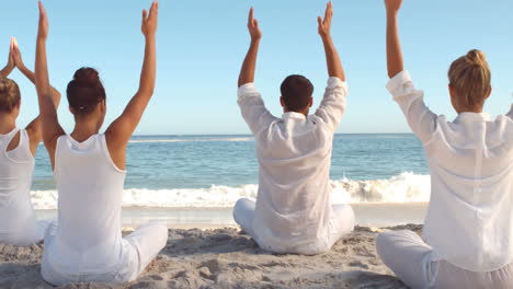 personas practicando yoga en la playa