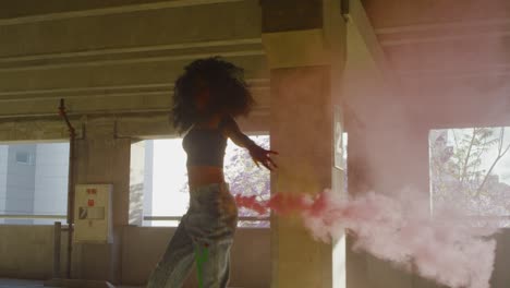 silhouette young woman dancing with colorful red smoke bomb in parking garage