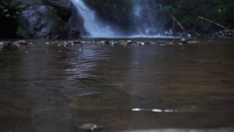 Superficie-De-Agua-Clara-Y-Ondulada-Con-Cascada-En-El-Fondo-En-Medio-Del-Bosque-De-Indonesia