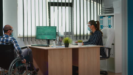 manager comming with wheelchair at workplace wearing mask