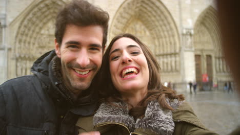 una pareja tomando una selfie frente a una iglesia.