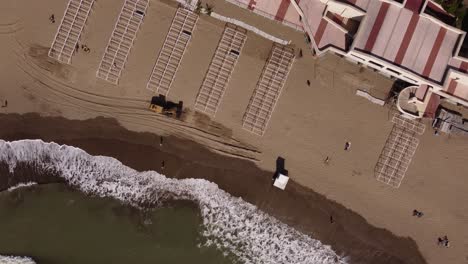 Antena-De-Arriba-Hacia-Abajo-De-La-Excavadora-Que-Lleva-Y-Deja-Caer-Arena-En-La-Playa-Durante-El-Día-Soleado,-Mar-Del-Plata,-Argentina