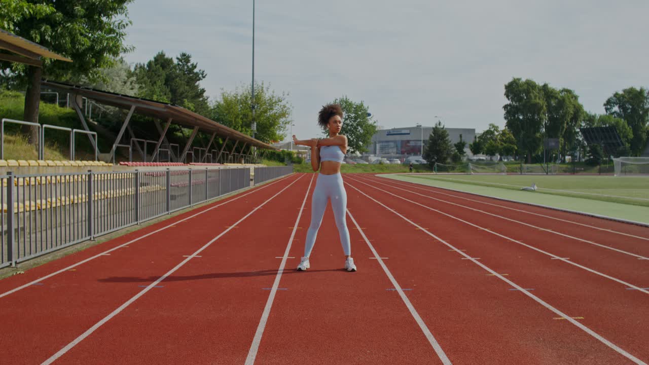 mujer estirándose en una pista de atletismo