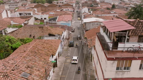 Aerial-footage-flying-close-over-buildings-with-cars-and-motorcycles-going-down-the-street