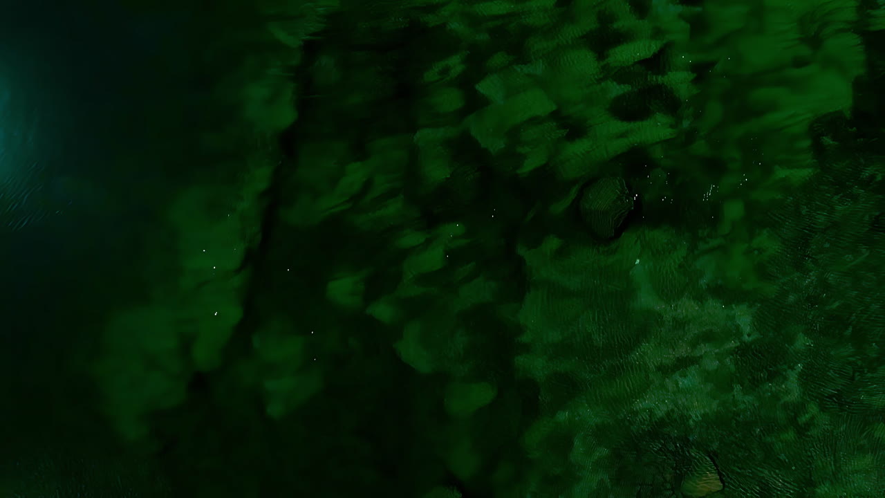 Aerial view over a deep green pool of christal clear water