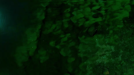 aerial view over a deep green pool of christal clear water