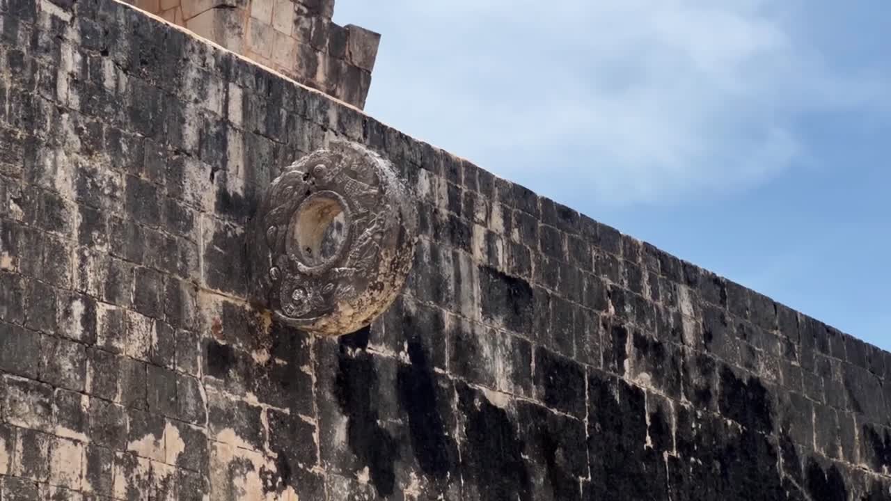 Handheld close-up panning shot of the stone ring at the Great Ball Court in Chichen Itza, Mexico. 4K