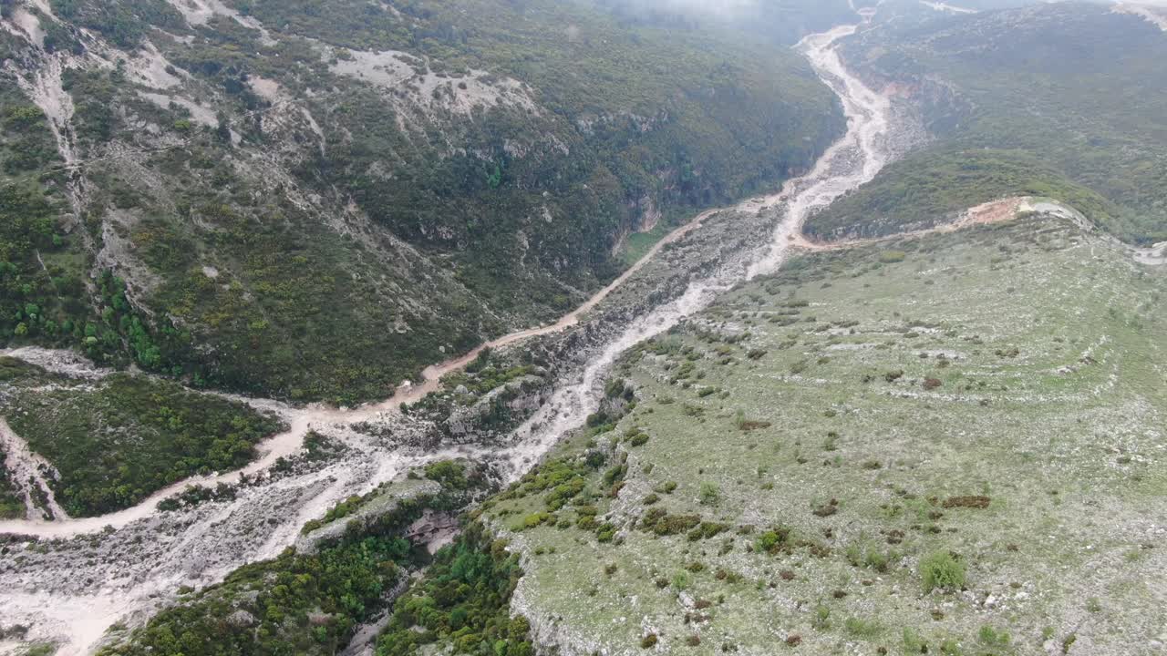 vista de avión no tripulado en albania volando sobre una montaña verde y rocosa desde la vista superior y ascendiendo a la nube y el océano azul en el horizonte