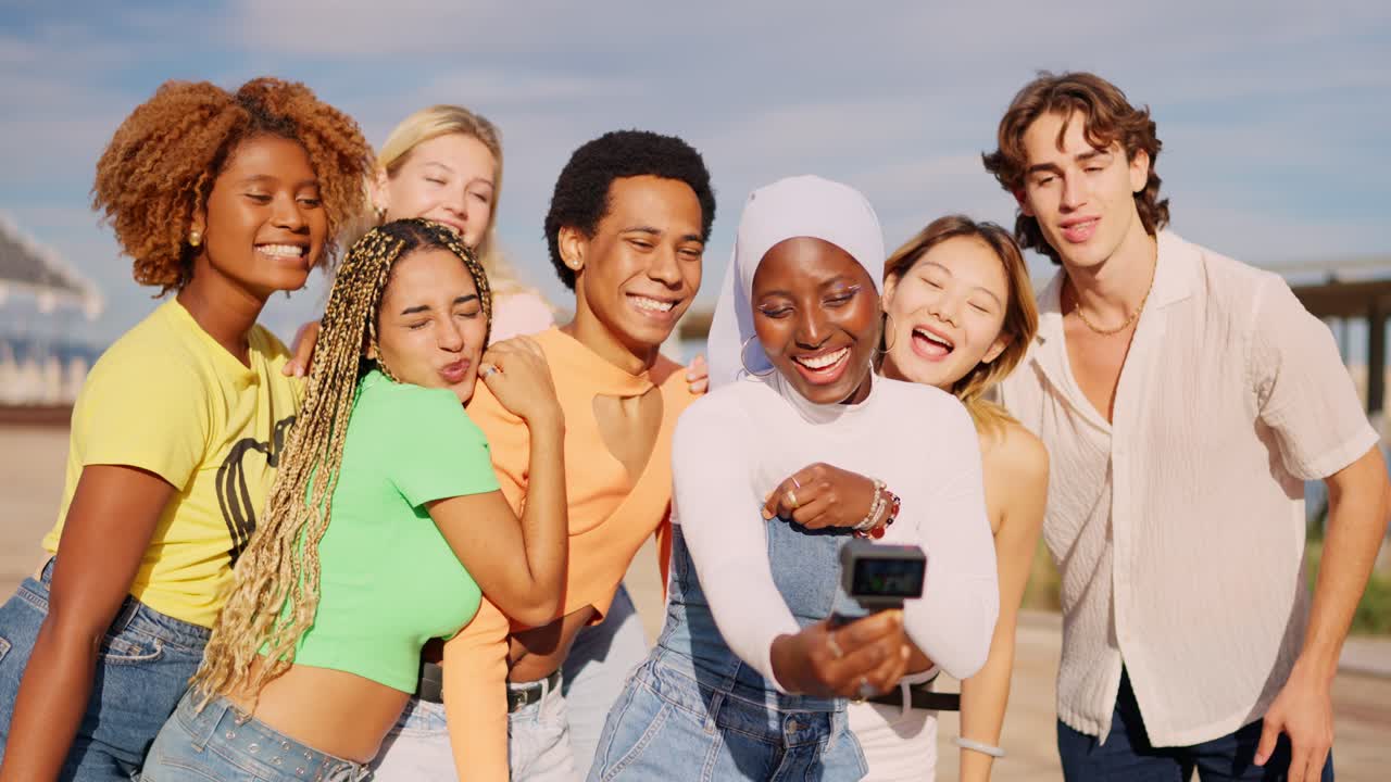 Multi-ethnic friends recording a video with small camera outdoors
