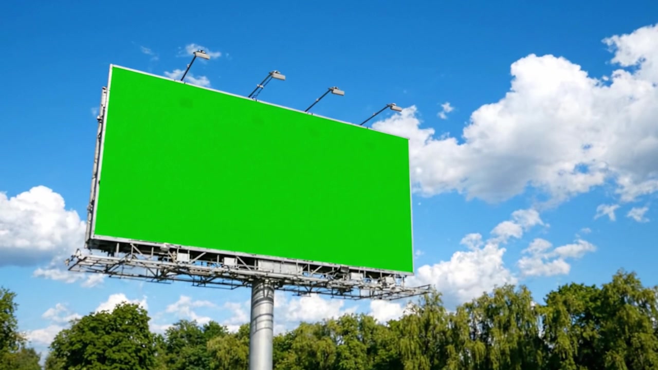 En Stor Grøn Billboard Skiller Sig Ud Mod en Klar Blå Himmel, Omgivet af Frodigt Grønt, Klar til Reklame eller Kreativitet