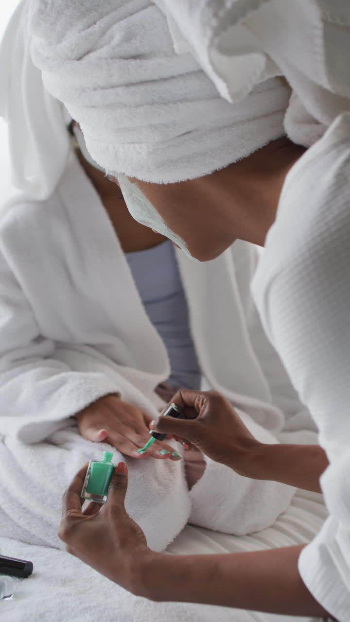 vidéo verticale de femmes biraciales heureuses en masques hydratants polissant les ongles