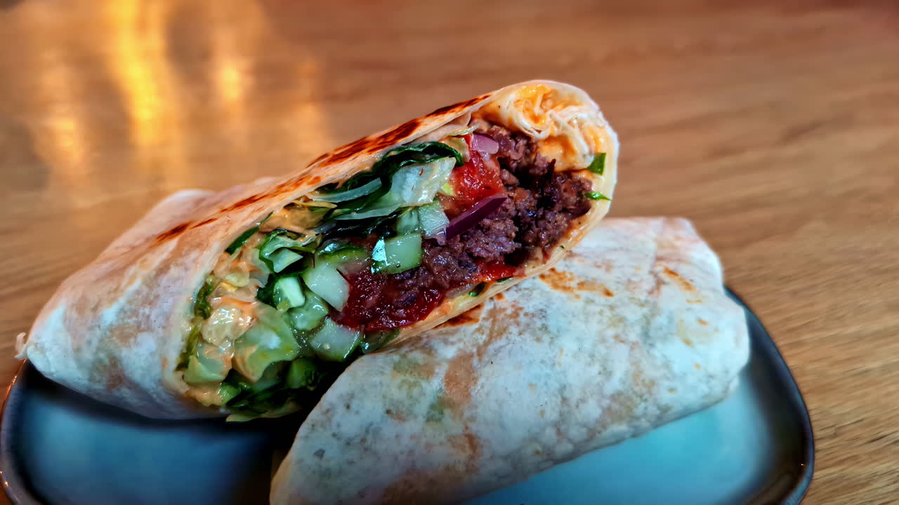 un primer plano de un pepino mexicano shawarma con salsa picante roja que se aleja de la mesa en un sándwich de restaurante
