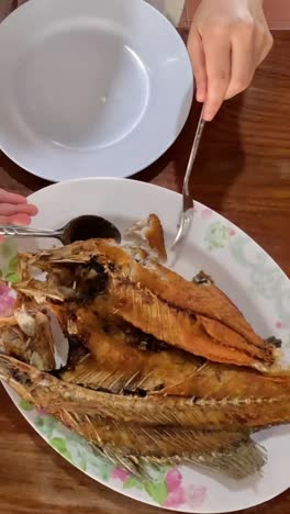 manos arreglando platos de pescado y camarones en la mesa