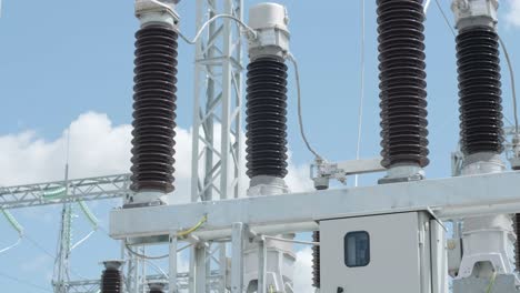 many high voltage electrical insulators in power substation against blue sky background