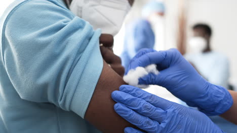 una doctora se prepara para vacunar a un paciente negro.