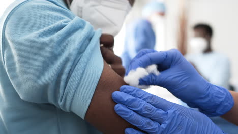 female doctor preparing to vaccinate black male patient