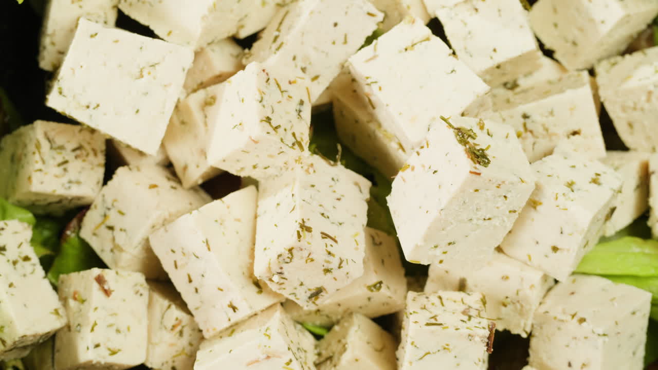 Fried tofu with sesame seeds and spices on cast iron pan, cooking japanese salad. Healthy ingredient for cooking vegan vegetarian diet food. Roasted tofu over black background.