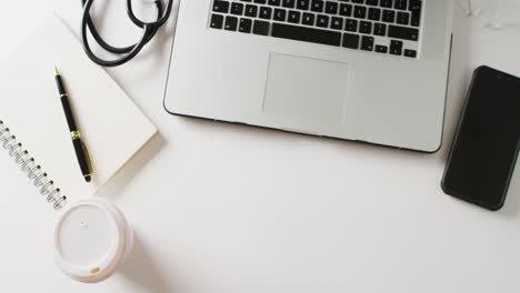 Video-of-laptop-with-coffee,-notebook-and-smartphone,-on-white-background-with-copy-space