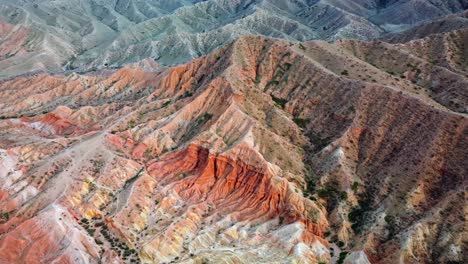 un dron volando sobre montañas rojas con diferentes tonos de rojo, capturando los picos escarpados y la belleza natural del paisaje