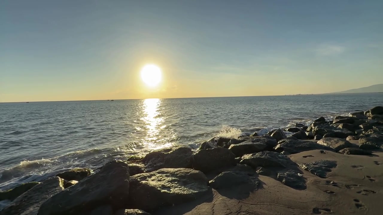 Gylden solnedgang over havet med bølger og klipper