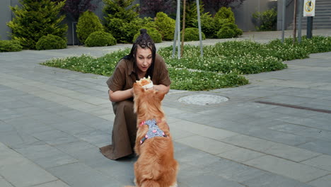 woman feeding a dog a sandwich in the city