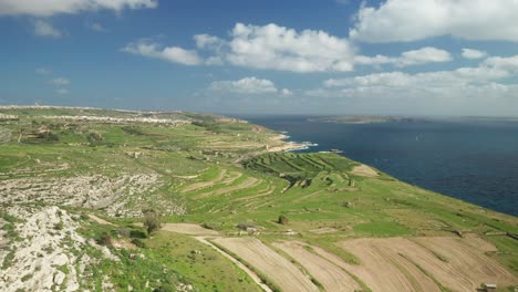 aerial: flying over ta cenc cliffs greenery plains near beautiful calm mediterranean sea