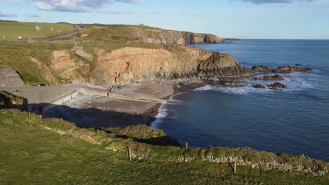 waterford copper coast, little sheltered beach called stage cove, with the copper coast drive in the background all the ruined remains of tankards town copper mines