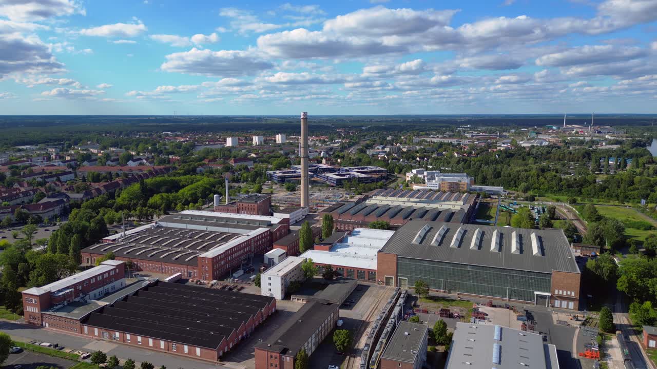 industrial buildings and a chimney in Hennigsdorf, Germany, with a train passing by. Spectacular aerial view flight panorama overview drone