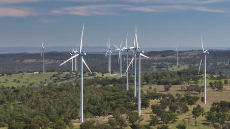 slow motion 4k drone over tall renewable energy wind turbines spinning above rural countryside in australia, slow motion