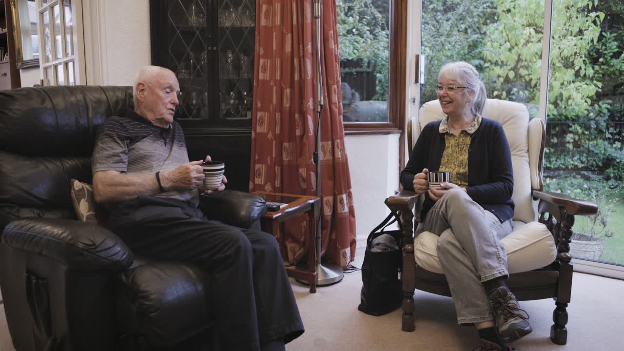 An elderly couple enjoying coffee and conversation in their living room