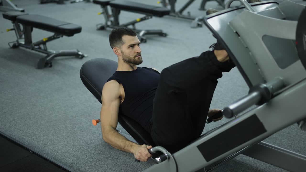 ejercicios de hombre muscular en un aparato de entrenamiento deportivo para los músculos de las piernas, levantamiento de pesas