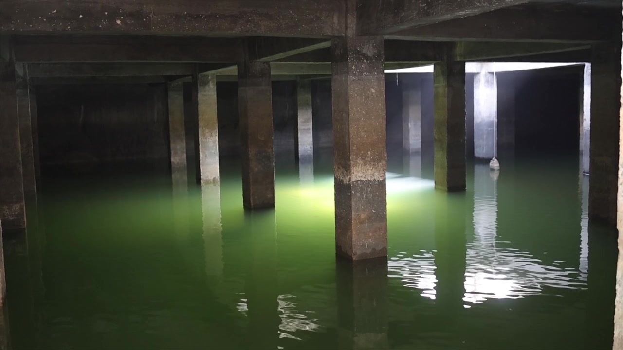 Underground Water Reservoir with Concrete Pillars and Submerged Lighting in Dark Industrial Tank.