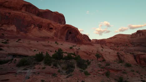 low drone shot flying towards the corona arch in moab, ut at sunset golden hour