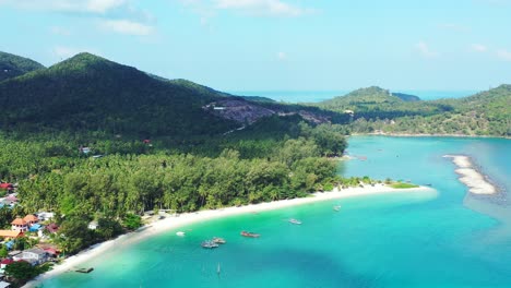 paradise beach with white sand washed by calm turquoise lagoon on tropical island with vacation resorts into green forest, thailand