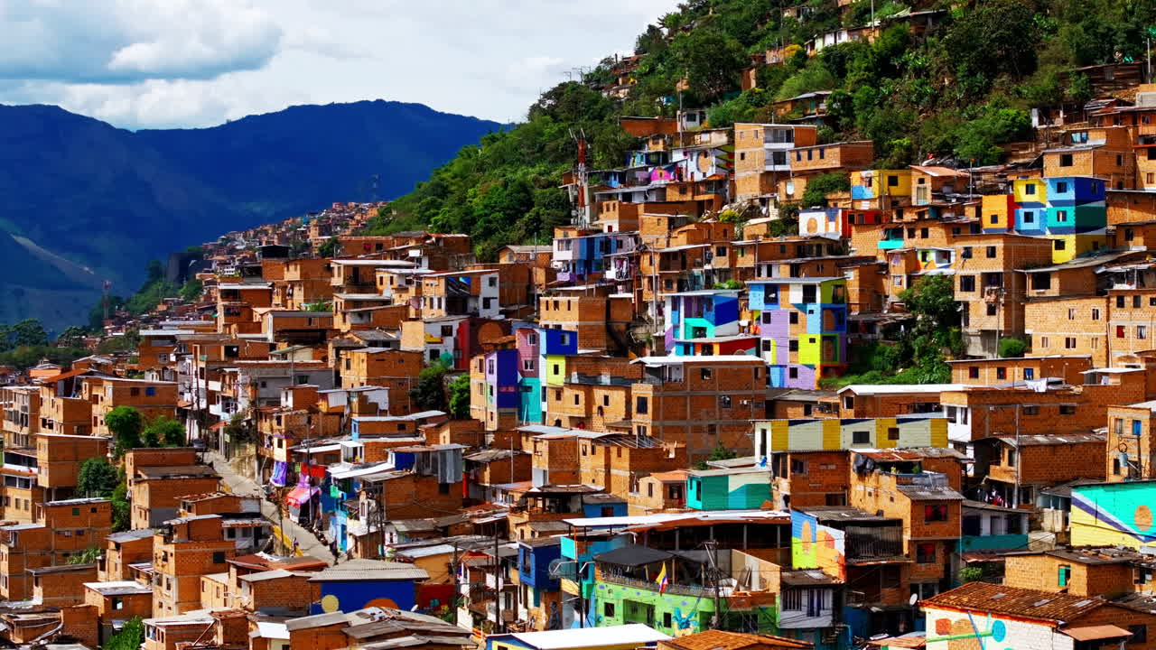 Riprese con drone su Medellín rivelano case colorate che si arrampicano sul fianco della collina, con facciate vivaci e fitte trame urbane dall'alto.