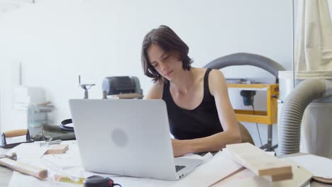 carpenter using laptop at desk in workshop 4k