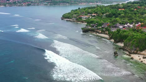 tropical ocean waves crashing at nusa ceningan island coastline, aerial top down